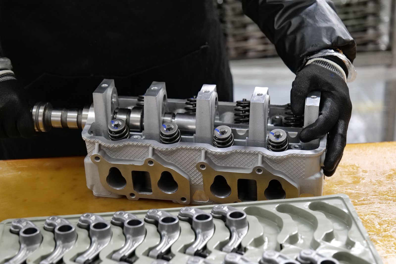 A machined engine cylinder head being handled at a bench in an automotive components plant.