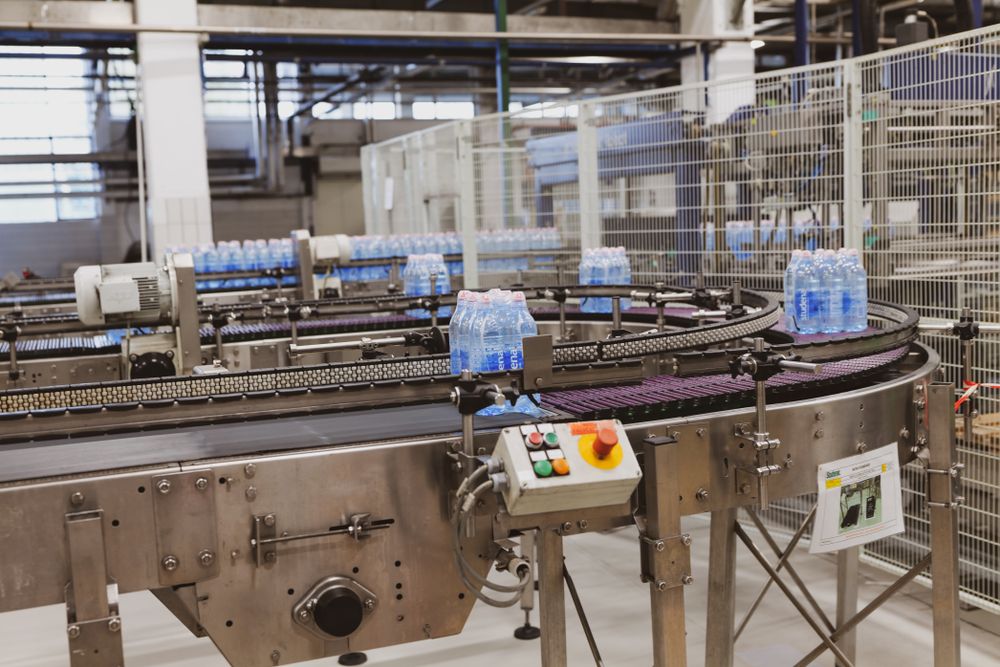 Packs of bottled water moving along a conveyor in a packaging plant.